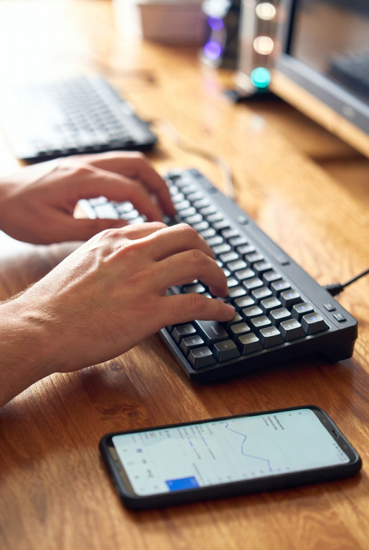 Cận cảnh đôi bàn tay đang gõ phím và điện thoại hiển thị biểu đồ tăng trưởng lượt xem YouTube